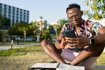 Obraz premium use mobile apps to organize your day, young man outdoors using his phone.