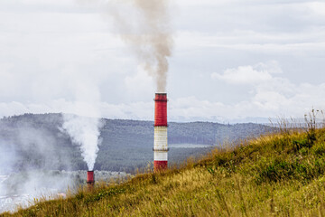 concept of environmental pollution. pipes with smoke on background of forest and mountain