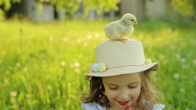Portrait of a girl with a chick is sitting on a girl's hat. Sunny Easter Holiday