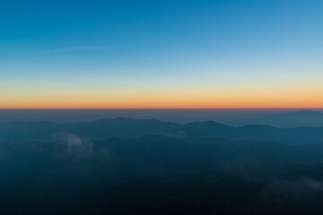 Panoramic twilight view while morning mist covered partly mountain seen from the highest peak of Doi Pha Hom Pok, Fang, Chiang Mai, Thailand.