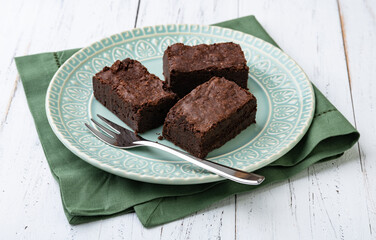 Brownies on a green plate over white wooden table