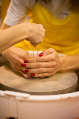 The hands of a young woman-a master of ceramics, working on a potter's wheel, making a plate of clay in her own art studio. Close-up, front view