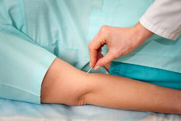 Doctor neurologist checking reflexes of female patient with needle in clinic. Doctor neurologist...