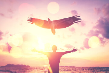 Man raise hand up on top of mountain and sunset sky with eagle birds fly abstract background. Copy...