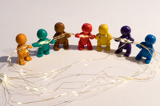 Figuren aus Knete halten eine Lichterkette, symbolische Darstellung f&uuml;r Zusammenhalt. 