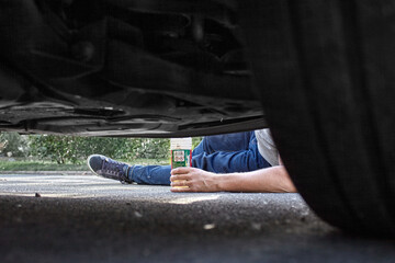 A mechanic on the ground, we can see his leg and arm holding a product. The picture has been taken...