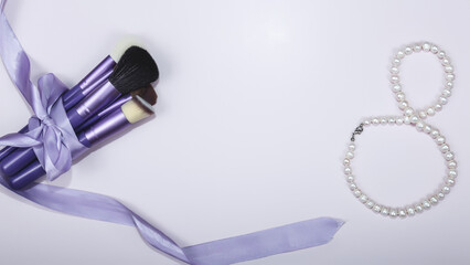 Women's Day make-up brushes. makeup brushes with violet ribbon on violet background. make-up artist for the tools.