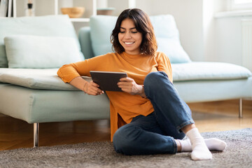 Smiling young arab woman relaxing with digital tablet at home