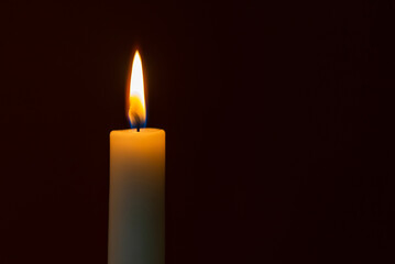 Candle flame on a dark background, symbol of prayer and remembrance.Religion concept.Closeup.Copy space.