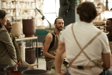Fototapeta na wymiar Smiling ceramists having a meeting in a pottery studio