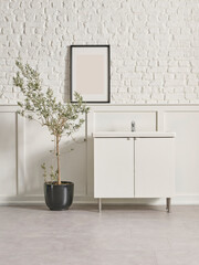 Bath room white cabinet, frame, black vase of plant olive tree, sink, white wall background.