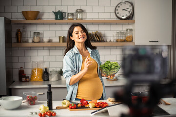 Obraz na płótnie Canvas Beautiful pregnant woman filming cooking vlog. Happy woman filming her blog about healthy food at home.
