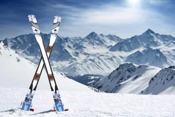 Fotobehang Snow-covered mountain range creates a picturesque winter wonderland - perfect for skiing and other winter sports.pair of skis stuck in the snow. Ai generated © Joaquin Corbalan