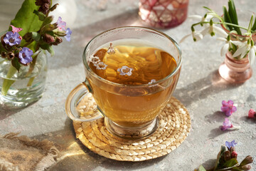 Fresh lungwort or pulmonaria flowers in a cup of herbal tea in spring