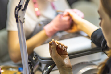 The manicurist cleans and removes the cuticle from the nail plate. Manicure process. Cut manicure technique. Special equipment for trimmed manicure.