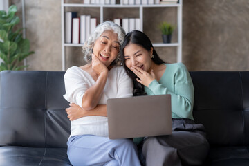 Asian mother and daughter using laptop for video call at home on vacation.