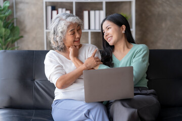 Asian mother and daughter using laptop for video call at home on vacation.