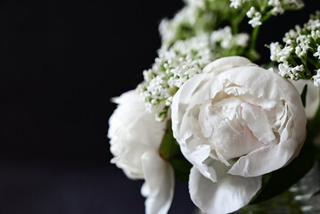 Fresh white peonies on a black, dark background. A condolence card. Wedding date. An invitation to a holiday. Congratulation.An empty space for text. View from above. He was lying flat.