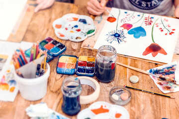 Painting Workshop. Artistic equipment: easel, paint brushes, tubes of paint, palette and paintings on work table in a artist studio.
