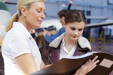 young female engineer reading book from teacher