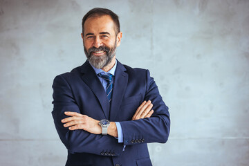 Mature businessman portrait. Successful businessman posing with crossed arms and smiling at camera....