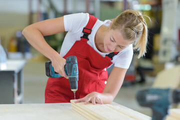 female carpenter drilling on wood