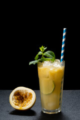 passion fruit cocktail, long drink decorated with mint on a dark background
