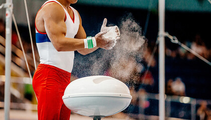 gymnast athlete hands applying gym chalk before exercise on horizontal bar