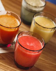 Freshly squeezed juices in colored glass glasses on wooden table