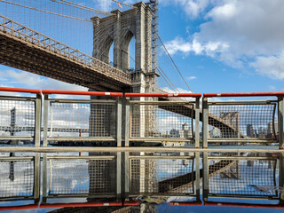 Reflection view of the Brooklyn Bridge between Manhattan and Brooklyn on a sunny day in New York...
