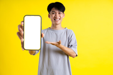 image of a handsome young man using his phone and posing on a yellow background