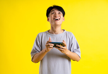 image of a handsome young man using his phone and posing on a yellow background