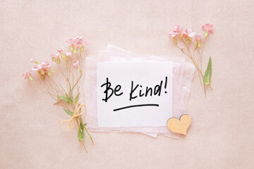 Be kind - card with text and flowers with heart on pink background, motivation phrase about goodness