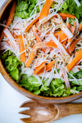 Hand mix fresh baby cos salad and crab stick in wood blow. Organic Vegetables mix lunch with green salad at kitchen table in wood cutting board.