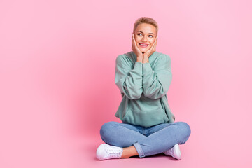 Obraz na płótnie Canvas Full length photo of adorable positive lady sitting floor look empty space interesting news empty space isolated on pink color background