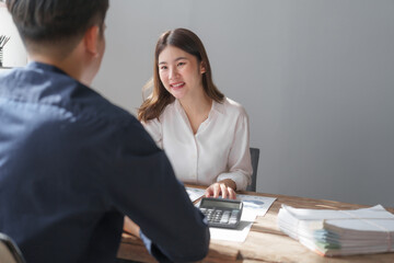 Team of asian people taxation bookkeeper consulting with friends analyzing balance sheet company annual financial report, tax of stock market statement in modern office.