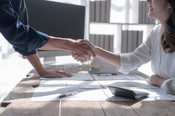 Team of asian people taxation bookkeeper consulting with friends analyzing balance sheet company annual financial report, tax of stock market statement in modern office. Shaking hands