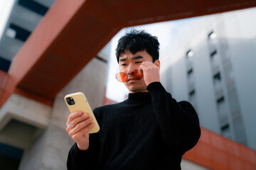 young asian man with cool red glasses looking at the mobile with surprise face life style