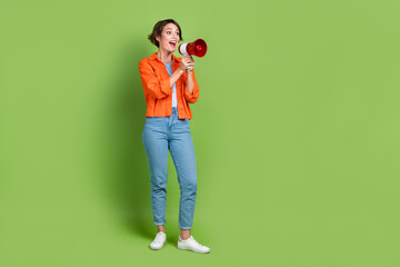 Fototapeta na wymiar Full length photo of pretty excited woman wear denim jacket screaming bullhorn empty space isolated green color background