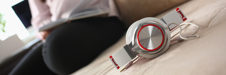 Fashionable white red headphones lie on the sofa in background person sits