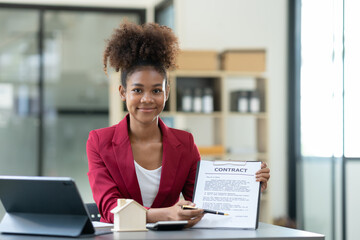 Smiling african american businesswoman, investor sitting at a desk showing and explaining the contract to the client for leasing a building or condo Sales, finance, marketing concepts