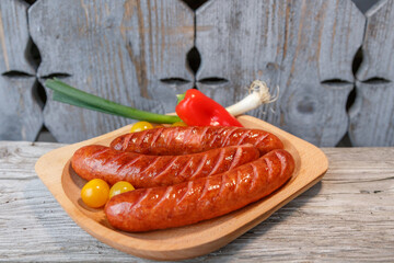Grilled sausage on wooden board with autentic wooden background in composition