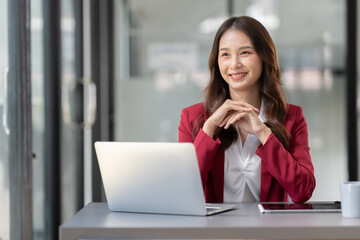 Beautiful Asian businesswoman working on a laptop computer doing financial, accounting analysis, reports, and data at the office.