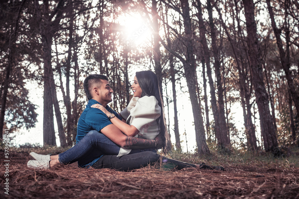 Wall mural Pareja joven latina abrazados en el piso sonriente con el sol a sus espaldas