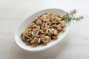 plate of cooked sea clams seasoned with rosemary, photo from the other close a on white rustic wood background , orizontal