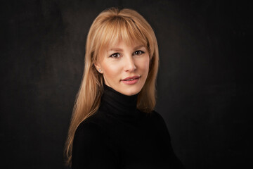 Heashot of an attractive middle age woman against dark background