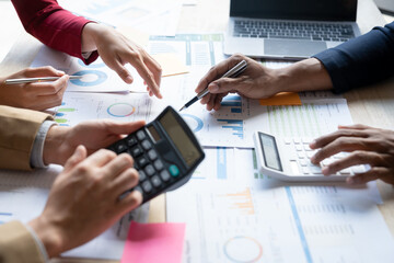 Fototapeta premium Teamwork of asian business people discussing and calculating with calculator on evaluation data in conference room. with the growth and pointing to the chart graph financial account.