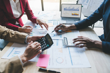 Teamwork of asian business people discussing and calculating with calculator on evaluation data in...