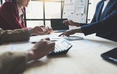 Teamwork of asian business people discussing and calculating with calculator on evaluation data in...