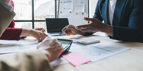 Teamwork of asian business people discussing and calculating with calculator on evaluation data in...